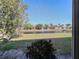 Backyard view of pond with water feature and green grass seen through screened window at 4721 Turnberry Cir, North Port, FL 34288