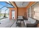 This outdoor patio features cozy wicker furniture, tile flooring, and a lovely lake view beyond its screened enclosure at 4918 Avon Ln, Sarasota, FL 34238
