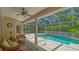 Screened-in pool area with ample seating, a ceiling fan, and lush greenery surrounding the pool at 5355 Anthony Ln, Sarasota, FL 34233
