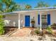 Inviting entryway with blue door and shutters, showcasing lush landscaping and brick walkway at 5432 Cape Leyte Dr, Sarasota, FL 34242