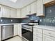 Modern kitchen with white cabinetry, stainless steel appliances, quartz countertops and subway tile backsplash at 5432 Cape Leyte Dr, Sarasota, FL 34242