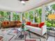 Bright living room featuring large windows with views of lush greenery, stylish sofas, and a patterned rug at 5432 Cape Leyte Dr, Sarasota, FL 34242