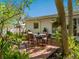 Inviting brick patio featuring an outdoor table surrounded by lush, mature tropical landscaping at 5432 Cape Leyte Dr, Sarasota, FL 34242