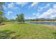Scenic backyard featuring a serene pond, lush green lawn, and glimpses of neighboring houses under a sunny sky at 5740 Sunflower Cir, Sarasota, FL 34238