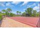 Outdoor basketball court with a red surface, black fence, and landscaping, near a lake at 5740 Sunflower Cir, Sarasota, FL 34238