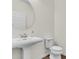 Bright bathroom featuring a pedestal sink, large round mirror and tiled floor at 5740 Sunflower Cir, Sarasota, FL 34238