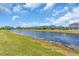 Picturesque view of a serene community pond lined with lush greenery and homes in the background under a blue sky at 5740 Sunflower Cir, Sarasota, FL 34238
