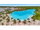 Aerial view of the beautiful Aqua community lagoon with palm trees, white sandy beach, and clear blue water at 5939 Redbay Blvd, Bradenton, FL 34210