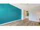 Spacious bedroom featuring new hardwood floors and a vibrant turquoise accent wall at 6157 Midnight Pass Rd # B42, Sarasota, FL 34242