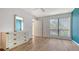 Bright and airy bedroom with new hardwood floors, a wicker dresser, and a large window at 6157 Midnight Pass Rd # B42, Sarasota, FL 34242