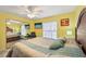 Bright bedroom with yellow walls, ceiling fan, mounted TV and closet with mirrored doors at 6330 Green Oak Cir, Bradenton, FL 34203