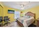 Bright bedroom with yellow walls, ceiling fan, mounted TV, and a wooden bed frame at 6330 Green Oak Cir, Bradenton, FL 34203