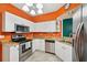 Well-lit kitchen with stainless steel appliances, white cabinetry, and colorful orange walls at 6330 Green Oak Cir, Bradenton, FL 34203