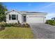 Charming single-story home with a manicured lawn, a gray driveway and a two-car garage under a clear sky at 8134 Shore Lake Dr, Englewood, FL 34224