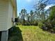 Grassy backyard with mature trees surrounding a light yellow home, showing the elevated foundation at 8297 Strasse Blvd, Punta Gorda, FL 33982