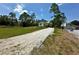 Gravel driveway leading to a cozy home surrounded by lush greenery and clear blue skies at 8297 Strasse Blvd, Punta Gorda, FL 33982