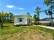 Quaint home with blue shutters nestled on a grassy lot with lush trees and a glimpse of the pool area at 8297 Strasse Blvd, Punta Gorda, FL 33982