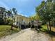 Charming home featuring a light yellow exterior, wooden deck, gravel driveway, and well-maintained landscaping at 8297 Strasse Blvd, Punta Gorda, FL 33982