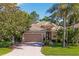 Charming single-story home with a tile roof, lush landscaping, and a brick driveway at 9120 Willow Brook Dr, Sarasota, FL 34238