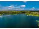 Aerial view of a lake surrounded by lush trees and houses with a bright blue sky above at 12676 Sagewood Dr, Venice, FL 34293