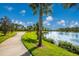 Scenic view of a lakefront walking path surrounded by lush greenery and palm trees at 12676 Sagewood Dr, Venice, FL 34293