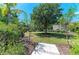 Lush backyard featuring a large tree, green grass, mulched garden areas, and a stone paver walkway at 12838 Daisy Pl, Bradenton, FL 34212