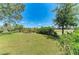 A grassy backyard with mature trees, landscape and a view of neighborhood homes at 12838 Daisy Pl, Bradenton, FL 34212