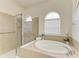 Elegant bathroom featuring a soaking tub, glass-enclosed shower, and tile surround at 12838 Daisy Pl, Bradenton, FL 34212
