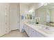 Bright bathroom with double sinks, white cabinetry, and a large mirror at 12838 Daisy Pl, Bradenton, FL 34212