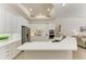 Modern white kitchen with stainless steel appliances, large island, and open floor plan to living areas at 12838 Daisy Pl, Bradenton, FL 34212