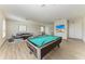 Spacious living room features a pool table, modern decor, and ample natural light; perfect for entertaining or relaxing at 12838 Daisy Pl, Bradenton, FL 34212