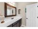 A powder room with a dark vanity, white counter and framed mirror with dark wood trim at 13116 Bliss Loop, Bradenton, FL 34211