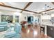 Bright open-concept living room features wood beams, piano, leather sofa, and access to outdoor pool area at 13116 Bliss Loop, Bradenton, FL 34211