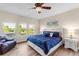Bright, airy main bedroom with wood-look flooring, ceiling fan, view of the backyard, and a comfy blue chair at 13116 Bliss Loop, Bradenton, FL 34211