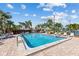 Community pool with brick paver deck, lounge chairs and mature palm trees on a bright day at 14519 Catalina Cir, Seminole, FL 33776
