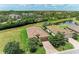 An aerial view of the home, revealing the terracotta roof, brick driveway, and adjacent pond at 157 Wandering Wetlands Cir, Bradenton, FL 34212