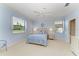 Light blue bedroom features a queen bed, and two windows bringing in natural light at 157 Wandering Wetlands Cir, Bradenton, FL 34212