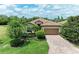 Beautiful single-story home featuring a terracotta-tiled roof, paver driveway, and lush tropical landscaping at 157 Wandering Wetlands Cir, Bradenton, FL 34212