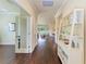 Hallway with hardwood floors, decorative shelving, and doorway views of the living room and office space at 157 Wandering Wetlands Cir, Bradenton, FL 34212