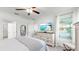 Bright bedroom with a ceiling fan, beach view on the TV, and lots of natural light at 17576 Holly Well Ave, Wimauma, FL 33598