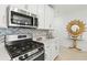 Modern kitchen features stainless steel appliances, white cabinets, quartz countertops, and stylish backsplash at 17576 Holly Well Ave, Wimauma, FL 33598