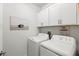 Functional laundry room with white washer and dryer and white cabinets for storage at 17576 Holly Well Ave, Wimauma, FL 33598