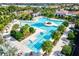 Stunning aerial view of the community pool and seating area surrounded by lush landscaping and trees at 17576 Holly Well Ave, Wimauma, FL 33598