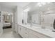Elegant bathroom featuring double sinks, white cabinetry, and a glass-enclosed shower at 17578 Holly Well Ave, Wimauma, FL 33598