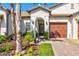 Charming single-Gathering home featuring a well-manicured lawn, colorful flowers, and attached garage at 17578 Holly Well Ave, Wimauma, FL 33598