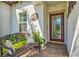 Inviting covered front porch with beautiful brick flooring, a decorative glass front door, and a comfortable bench at 17578 Holly Well Ave, Wimauma, FL 33598