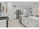 Spacious kitchen showcasing stainless steel appliances, modern countertops and seamless transition to living area at 17578 Holly Well Ave, Wimauma, FL 33598