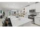 Bright kitchen with white cabinetry, stainless steel appliances, island seating, and an open floor plan to living room at 17578 Holly Well Ave, Wimauma, FL 33598