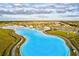 Panoramic aerial shot of a vibrant blue lagoon winding through a community with lush green surroundings at 17578 Holly Well Ave, Wimauma, FL 33598