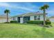 View of a backyard with lush green grass, tropical palm trees, and an outdoor screened-in patio area at 17732 Wayside Bnd, Punta Gorda, FL 33982